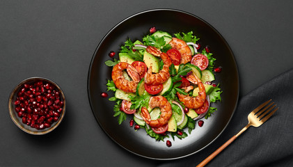 Shrimps salad, avocado, lettuce, cherry tomatoes. Home made vegetarian shrimp salad. Seafood concept. Tasty veg mixed leaves, grilled prawn shrimps in plate on black background.