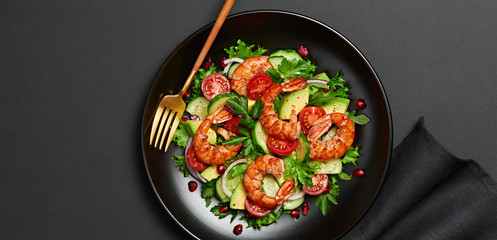 Shrimps salad, avocado, lettuce, cherry tomatoes. Home made vegetarian shrimp salad. Seafood concept. Tasty veg mixed leaves, grilled prawn shrimps in plate on black background.