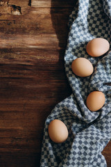 brown chicken eggs on a vintage background. On the side lies a blue linen cloth