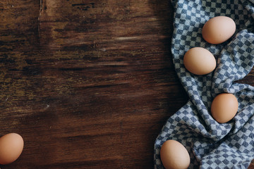 brown chicken eggs on a vintage background. On the side lies a blue linen cloth