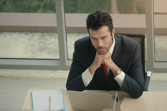 Businessman resting chin on hands, seriously thinking about job on messy desk at office desk conference meeting room in office, employee officer working at the workplace, feeling stressed and tired af