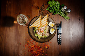 Caesar salad on black plate on wooden table.Top view