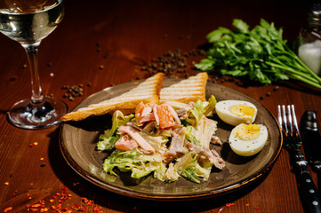 Caesar salad on black plate on wooden table