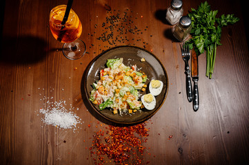 Caesar salad on black plate on wooden table.Top view