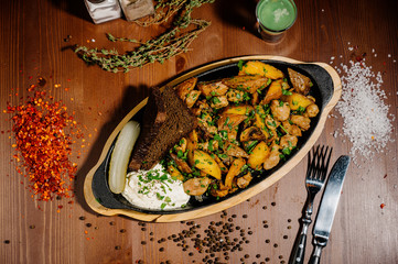 fried potatoes with meat on a plate on a wooden table.Top view