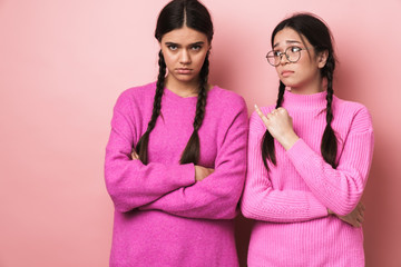 Image of two offended teenage girls with braids standing with arms crossed