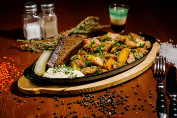 fried potatoes with meat on a plate on a wooden table