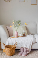 Spring home cozy interior. A bouquet of flowers in a vase, a cup of tea, decor on the sofa.