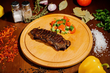 A juicy piece of fried meat lies on a cutting board against a wooden table.
