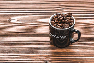 full black cup with coffee beans on brown wooden background. the inscription Espresso