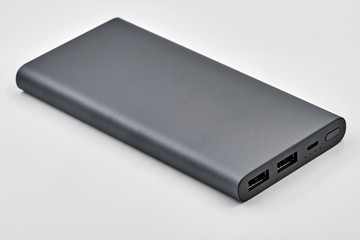 External dark powerbank with two usb outputs on a white background. Powerbank for charging mobile devices. Closeup