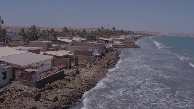 Pullback panoramic aerial drone view of houses on Colan Beach at a sunny day in Piura Region, Peru