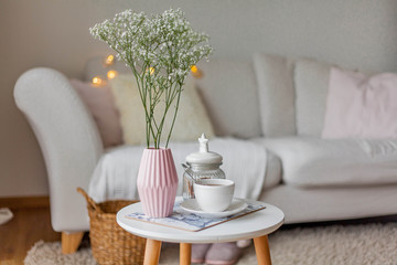 Spring home cozy interior. A bouquet of flowers in a vase, a cup of tea, decor on a coffee table.