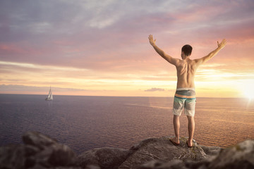 Fototapeta na wymiar Happy man with raised arms on top of a sea cliff