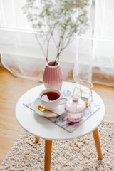 Fototapeta na wymiar Spring home cozy interior. A bouquet of flowers in a vase, a cup of tea, decor on a coffee table.