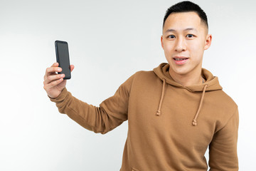 portrait of an asian man holding a smartphone in his hand on a white background