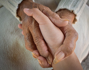  Hands of two people represent family warmth and care for the elderly.