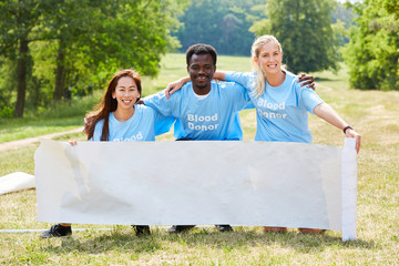 Group of blood donors is holding blank poster
