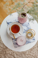 Spring home cozy interior. A bouquet of flowers in a vase, a cup of tea, decor on a coffee table.