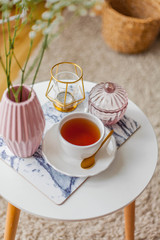 Spring home cozy interior. A bouquet of flowers in a vase, a cup of tea, decor on a coffee table.