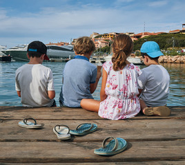 Children kids enjoying the summer with ice cream and flip-flops next to the sea on a pier