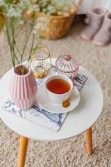 Spring home cozy interior. A bouquet of flowers in a vase, a cup of tea, decor on a coffee table.
