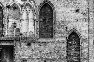 Fototapeta na wymiar The internal white painted wall of a destroyed church with bricked up arches.