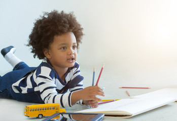 Lovely african boy happy drawing a toy in room.