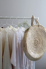 Obraz premium Capsule wardrobe in white and neutral colors and fashionable straw bag. Selective focus.