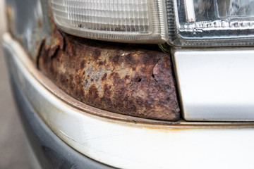 Paint bubbles, cracked paint and rust. White car headlamps
