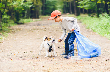 Earth day concept with kid and dog cleaning park gathering plastic bottles