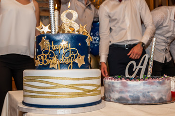 18 birthday party. Gold and blue fondant birthday cake with number 18 on the top over the party...