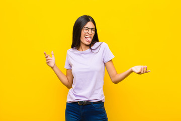 young pretty latin woman shrugging with a dumb, crazy, confused, puzzled expression, feeling...