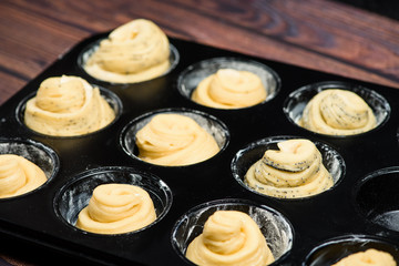 raw cruffins before baking in the oven in an iron mold. puff pastry croissant similar to a muffin rolled into a roll. modern baking. close-up, space for text. horizontal frame