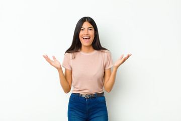 young pretty latin woman feeling happy, excited, surprised or shocked, smiling and astonished at...