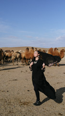 beautiful woman national eastern clothes black color,veil,hijab,abaya ornament her head,portrait steppes camels,strong wind,desert,wildlife,well,decoration,caucasian,slow ,sun