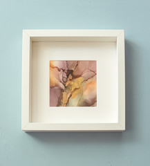 Abstract colorful picture in white frame on the wall. Mixing acrylic paints. Modern art. Marble texture. Alcohol ink colors translucent.Alcohol Abstract contemporary art fluid.