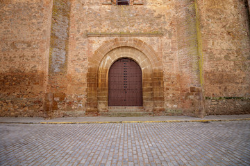 Large arched wooden door at the rear of an old church in Spain