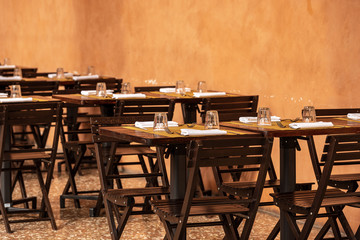 Bologna, typical outdoor (under a colonnade) restaurant table with paper tablecloth, cutlery, glasses and white napkins. Emilia-Romagna, Italy, Europe