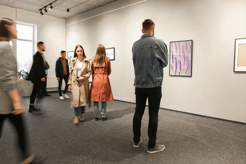 Exhibition in modern crowded art gallery