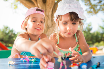 Two little cute girls playing dolls outdoors