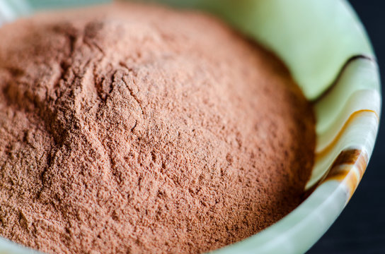 Red bentonite clay powder in the onyx bowl. Diy facial mask and body wrap recipe. Natural beauty treatment and spa. Clay texture closeup, selective focus.