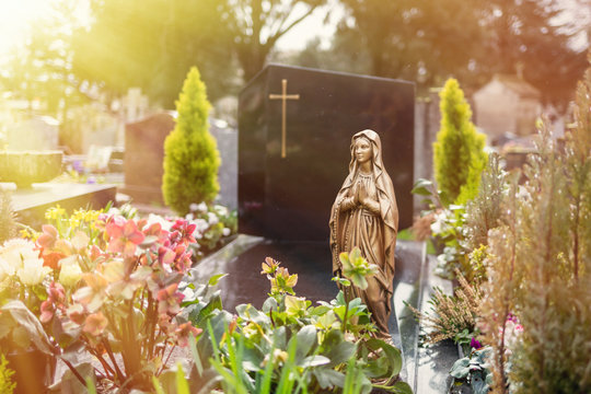 Virgin Mary at cemetery, graveyard background, tombstone, sunlight tone