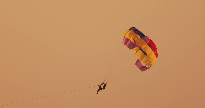 Parasailers Flying On Colorful Parachute In Sunset Or Sunrise Sky. Active Hobby