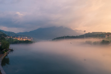 In the early morning of the city, the sky is full of rosy clouds, and the advection fog flows around the river, hazy and beautiful