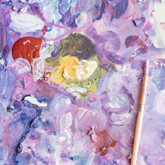 Tools of the artist. Palette, paints, brushes during use. Creativity and painting.