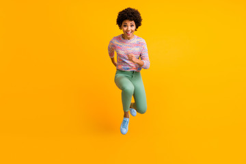 Full size photo of crazy dark skin curly lady jumping high rush fast discount shopping black friday low prices wear colorful pullover green pants shoes isolated yellow color background