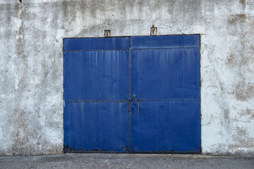 blue metallic door at the entrance of a old wharehouse  in village in Spain