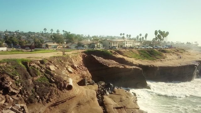 Aerial flying over pacific ocean cliffs towards condos on the San Diego shore