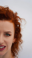 Green eyes of a beautiful red-haired curly-haired girl. long eyelashes, make up eyebrows. a look into the future. emotions, joy, laughter, fun. White background